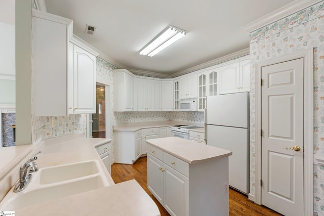 kitchen featuring a sink, a kitchen island, white appliances, wallpapered walls, and glass insert cabinets