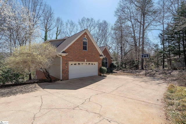 view of home's exterior with concrete driveway, an attached garage, brick siding, and roof with shingles