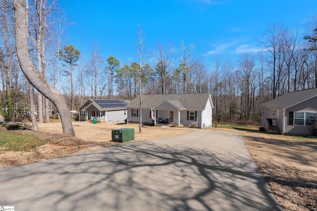 ranch-style home with roof mounted solar panels and driveway