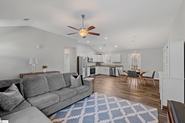 living room featuring visible vents, lofted ceiling, dark wood-type flooring, and ceiling fan with notable chandelier