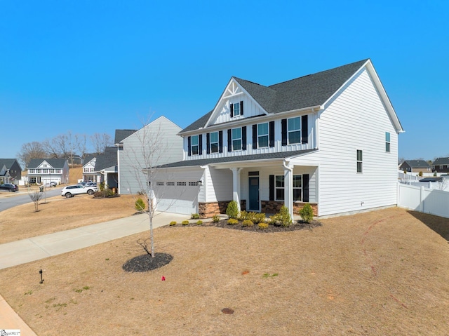 view of front of house with fence, driveway, covered porch, stone siding, and a residential view