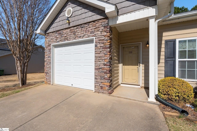 doorway to property featuring stone siding, driveway, and an attached garage