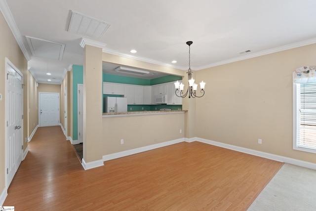 interior space with attic access, crown molding, light wood-style floors, and visible vents