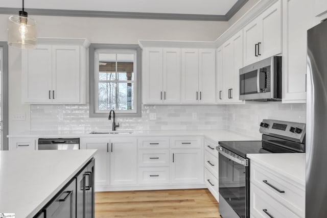 kitchen featuring light countertops, white cabinets, appliances with stainless steel finishes, and a sink