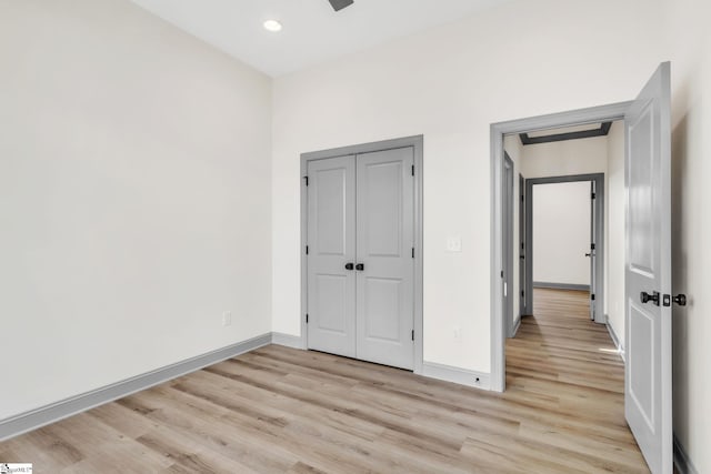 unfurnished bedroom with recessed lighting, a closet, baseboards, and light wood-style floors