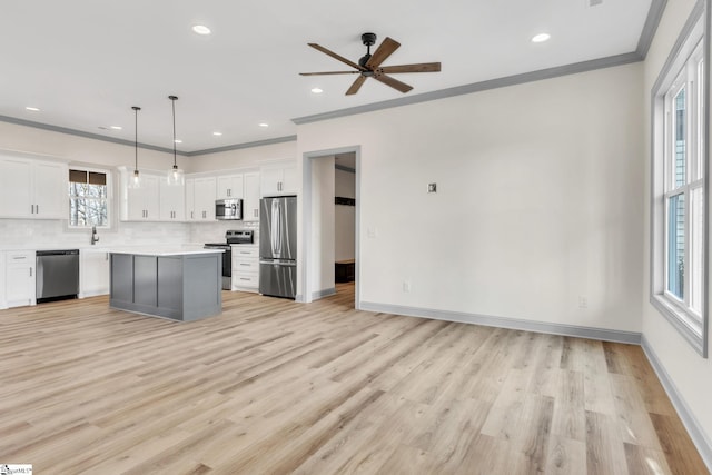 kitchen with tasteful backsplash, ceiling fan, ornamental molding, white cabinets, and stainless steel appliances