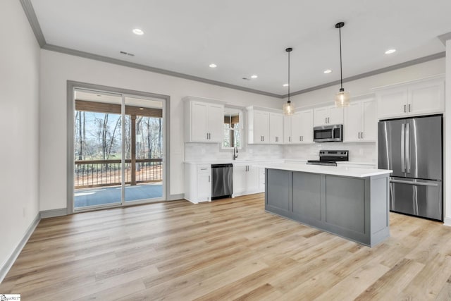 kitchen featuring ornamental molding, decorative backsplash, light countertops, stainless steel appliances, and white cabinetry