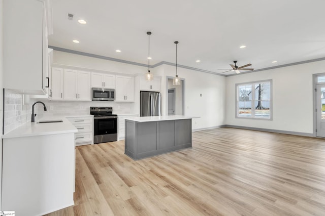 kitchen with a ceiling fan, a sink, a kitchen island, appliances with stainless steel finishes, and decorative backsplash