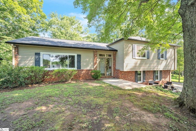 tri-level home with a patio area and brick siding