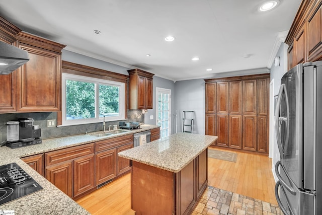 kitchen with ornamental molding, a kitchen island, appliances with stainless steel finishes, and a sink