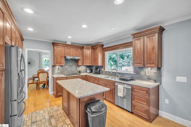 kitchen with ornamental molding, under cabinet range hood, a sink, appliances with stainless steel finishes, and baseboards