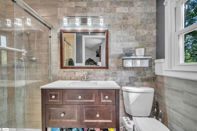 bathroom featuring toilet, tile walls, a stall shower, and vanity