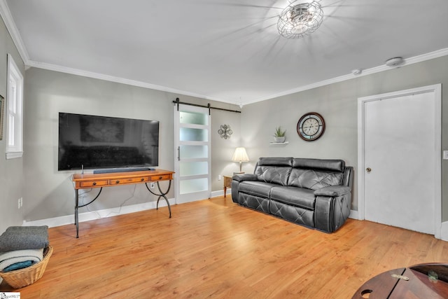 living area with ornamental molding, baseboards, a barn door, and wood finished floors