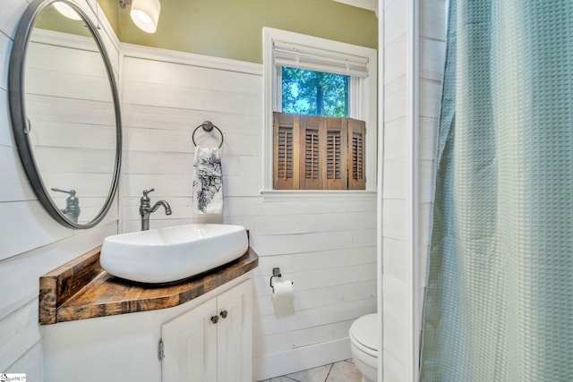 bathroom with vanity, wooden walls, a shower with curtain, tile patterned flooring, and toilet