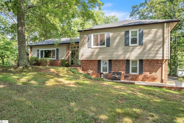 tri-level home featuring brick siding and a front lawn