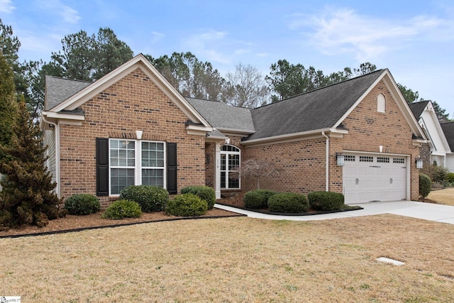 traditional home with roof with shingles, concrete driveway, an attached garage, a front yard, and brick siding