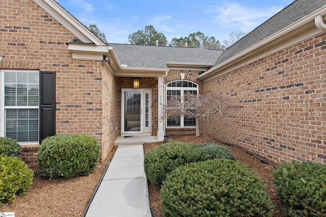 entrance to property with brick siding and roof with shingles