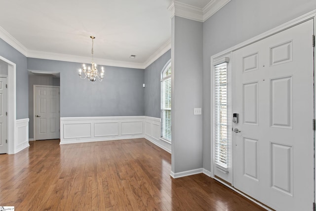 foyer featuring a wainscoted wall, an inviting chandelier, wood finished floors, and crown molding