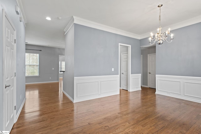 unfurnished dining area with an inviting chandelier, wood finished floors, and ornamental molding