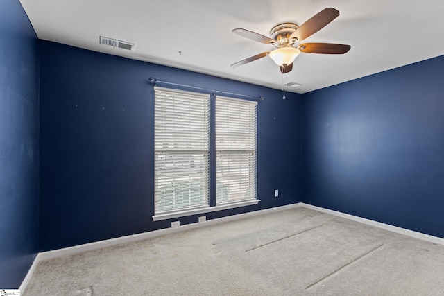 carpeted empty room with visible vents, baseboards, and ceiling fan