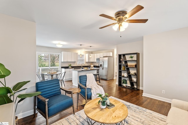 living room featuring baseboards, wood finished floors, and a ceiling fan