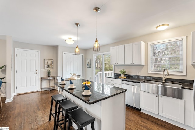 kitchen with a sink, dishwasher, pendant lighting, a kitchen breakfast bar, and dark wood-style flooring