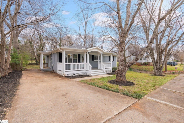 bungalow with a porch, concrete driveway, and a front lawn