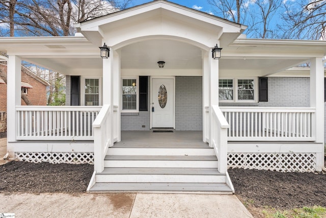 doorway to property featuring brick siding and covered porch