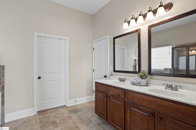 bathroom with double vanity, baseboards, tile patterned floors, and a sink