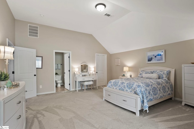 bedroom featuring visible vents, light carpet, ensuite bathroom, and vaulted ceiling