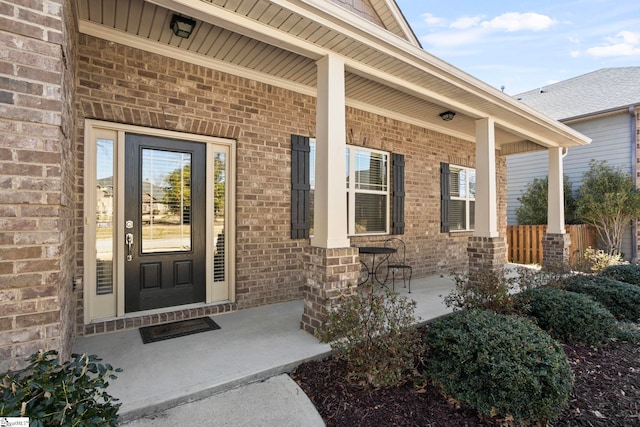 doorway to property featuring brick siding and covered porch