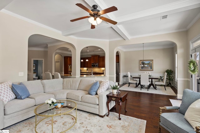 living room featuring dark wood finished floors, visible vents, arched walkways, and a ceiling fan