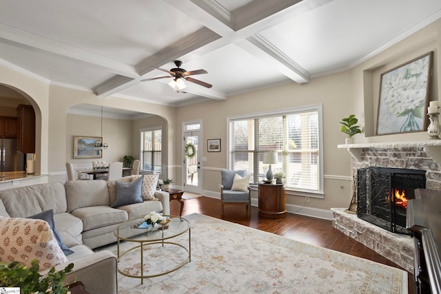 living area with arched walkways, beamed ceiling, and dark wood finished floors