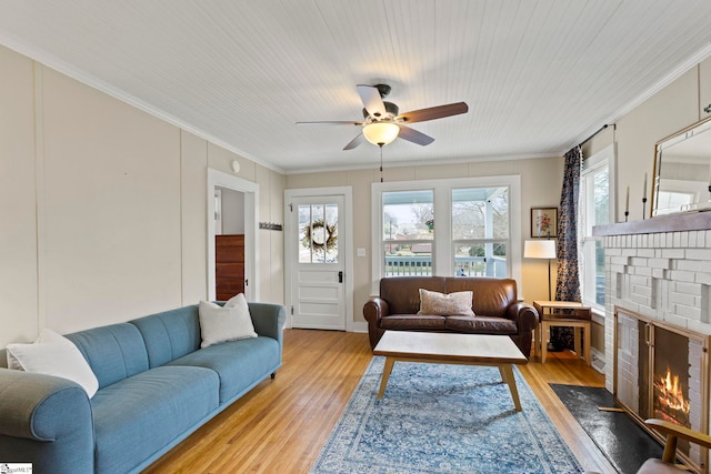 living room with plenty of natural light, a ceiling fan, light wood-style floors, and ornamental molding