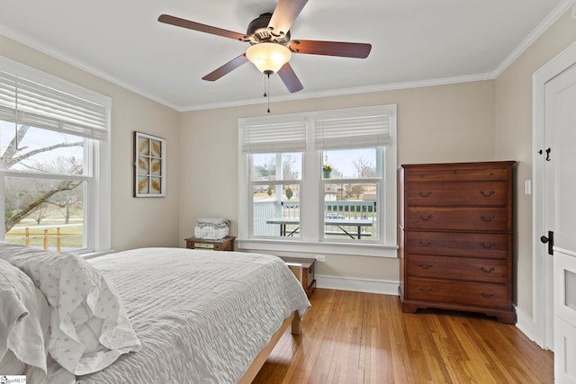 bedroom with crown molding, a ceiling fan, baseboards, and light wood finished floors