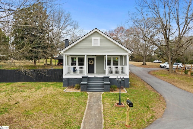 bungalow-style home featuring driveway, a front lawn, a porch, crawl space, and a chimney