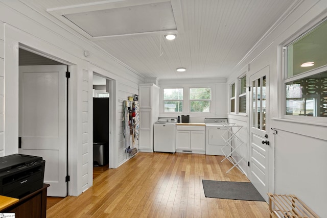 kitchen featuring light wood-type flooring, washer / dryer, ornamental molding, and white cabinetry