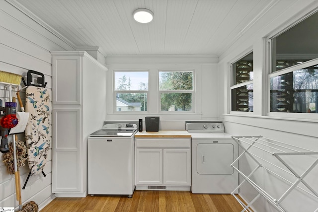 clothes washing area featuring light wood finished floors, visible vents, cabinet space, and crown molding