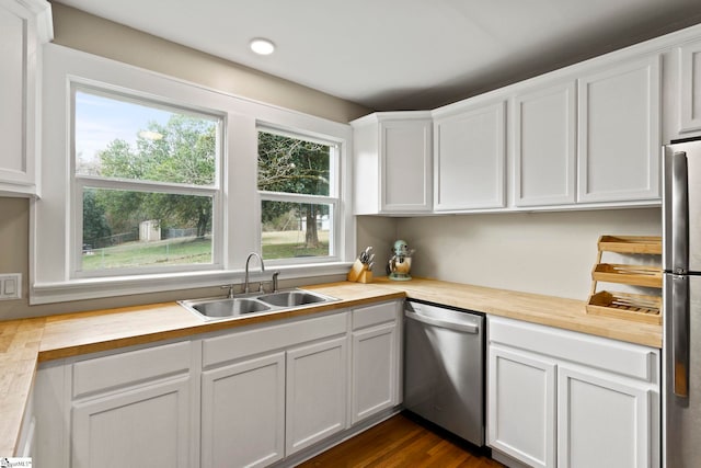 kitchen with dark wood-type flooring, butcher block countertops, a sink, white cabinetry, and appliances with stainless steel finishes