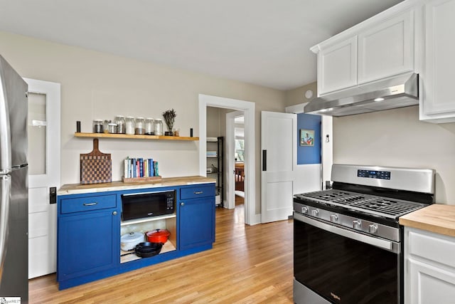 kitchen featuring blue cabinets, under cabinet range hood, light wood-type flooring, stainless steel appliances, and wood counters