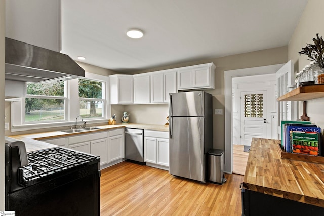 kitchen with light wood-type flooring, stainless steel appliances, wood counters, and a sink