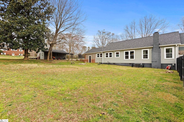 rear view of property with a yard, central AC unit, an outdoor structure, and fence