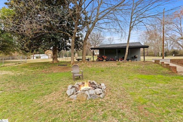 view of yard with an outdoor structure, a fire pit, and fence