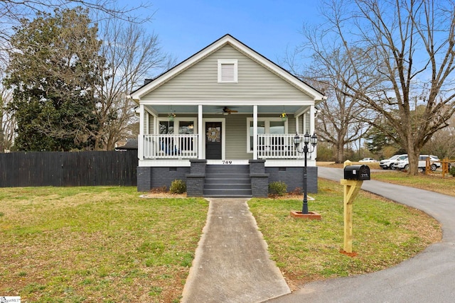 bungalow-style home featuring a ceiling fan, a front lawn, fence, covered porch, and crawl space