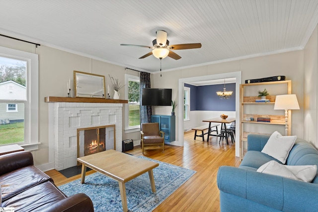 living room with plenty of natural light, light wood-style floors, ornamental molding, and a fireplace