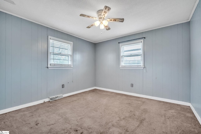 spare room featuring visible vents, carpet, a ceiling fan, and crown molding