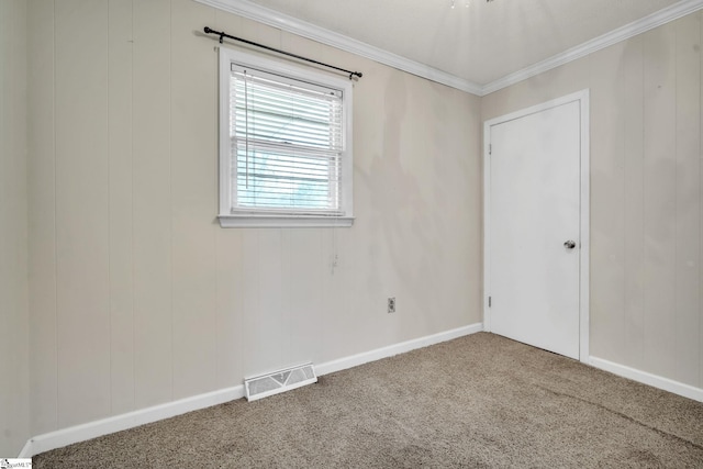 carpeted spare room with visible vents, baseboards, and ornamental molding