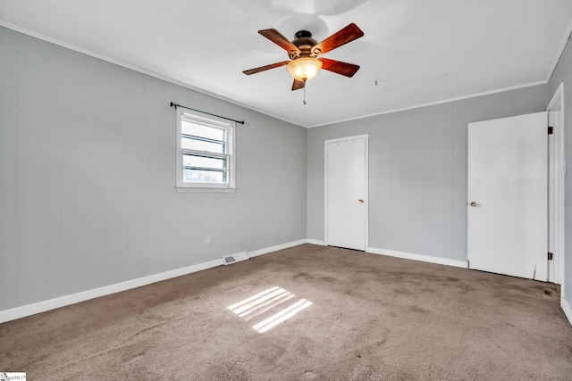 unfurnished bedroom with a ceiling fan, visible vents, carpet floors, and ornamental molding