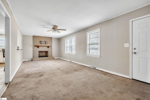 unfurnished living room featuring visible vents, ornamental molding, a ceiling fan, a textured ceiling, and carpet flooring