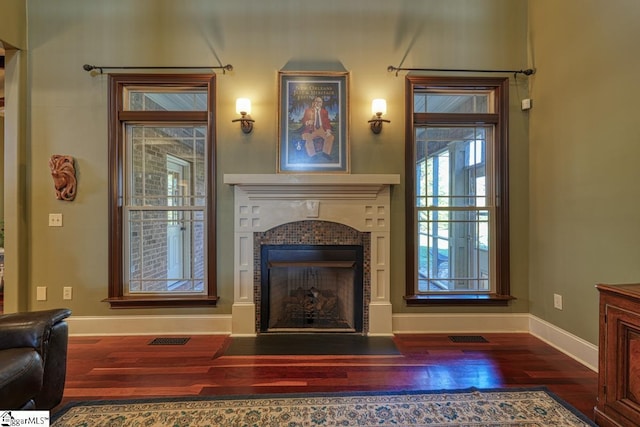 living room with visible vents, a tile fireplace, baseboards, and wood finished floors